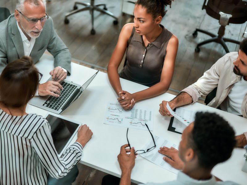 top-view-of-multicultural-team-discussing-business-while-sitting-at-the-office-table-together.jpg